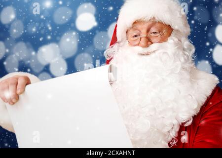 Babbo Natale che legge la lista dei desideri su sfondo a colori Foto Stock