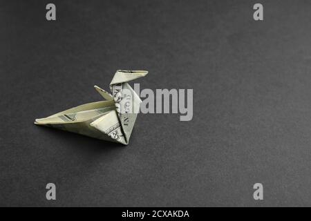 Uccello Origami fatto di banconota da dollaro su sfondo nero Foto Stock