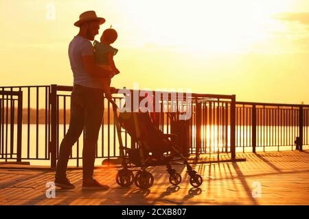 L'uomo e il suo bambino carino in passeggino vicino al fiume Foto Stock