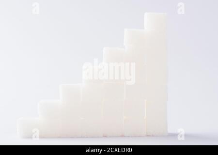 Pila ascendente di cubi di zucchero grafico, studio girato isolato su sfondo bianco, salute elevato rischio di diabete concetto Foto Stock