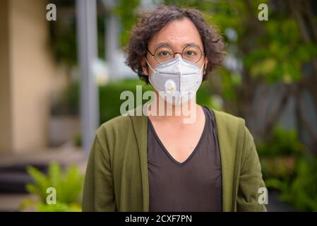 Uomo giapponese con capelli ricci che indossa la maschera sul tetto giardino Foto Stock