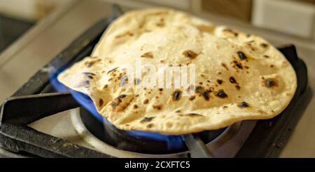 Chapati di grano o roti cotti al fuoco con un gas piano cottura Foto Stock