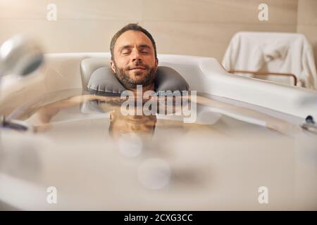 Giovane uomo bearded che prende il bagno nel salone del centro benessere Foto Stock