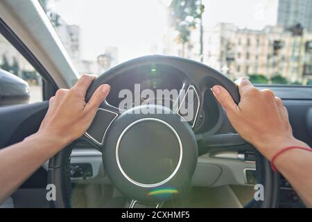 Donna che guida per le strade della città, primo piano di mani femminili sul volante Foto Stock