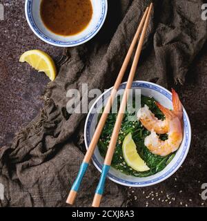 Ciotole cinesi con spinaci cotti e gamberi fritti con semi di limone e sesamo, salsa di soia e bastoncini di pollo su fondo di vecchio metallo. Stile asiatico Foto Stock