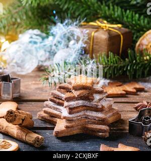 Stack di shortbread natalizi fatti in casa a forma di stella biscotti zucchero diverso Taglia con polvere di zucchero su vecchia superficie di legno con Natale arredamento e abete tr Foto Stock