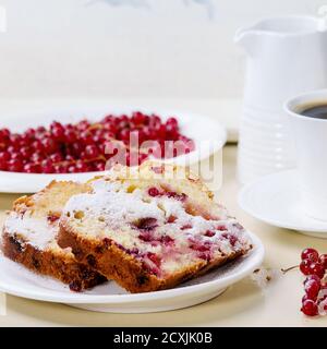 Tema della colazione. Due pezzi di torta fatta in casa con ribes rosso, serviti su piatto bianco con zucchero in polvere, frutti di bosco freschi, tazza di caffè e caraffa di latte o Foto Stock