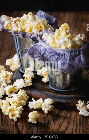 Preparate popcorn salata è servita in piccole benne con all'interno di carta su legno tagliere su legno scuro dello sfondo. Foto Stock