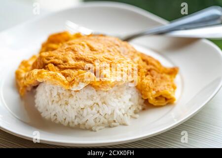 Facile menu di piatti thailandesi, omelette thailandesi su riso o Kai Jeaw Rad Kow. Primo piano omelette thailandesi su riso bianco in piatto bianco sul tavolo. Foto Stock