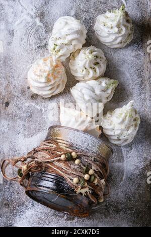 Meringa francese bianca fatta in casa come abete di Natale decorato da zucchero colorato e tee matcha da scatola regalo può over polvere vecchio metallo di fondo wi Foto Stock