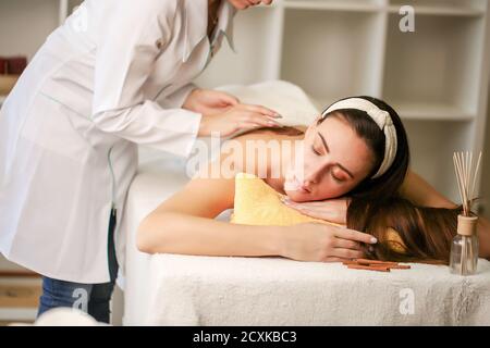 Concetto di trattamento di bellezza. Spa per il corpo, salute e relax, centro termale. Il massaggiatore effettua un massaggio del corpo femminile. Foto Stock