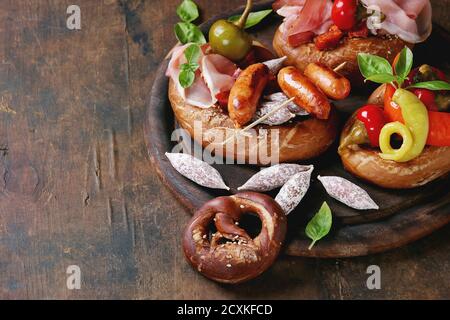Varietà di spuntini a base di carne salsicce fritte, wienerwurst, prosciutto, marinato al peperoncino servito in salati salatini con basilico fresco su legno tagliere uovere Foto Stock