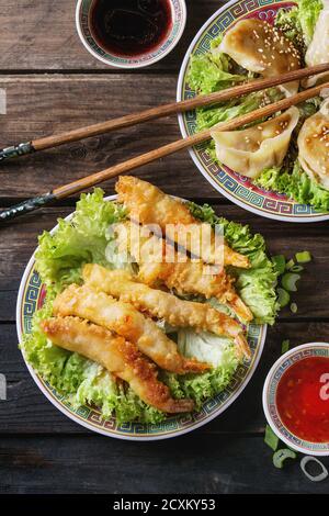 Fritto in tempura di gamberetti e gyozas potstickers su insalata di lattuga con salse e riso. Servita in Cina tradizionale con piastra su bastoncini di legno vecchio Foto Stock