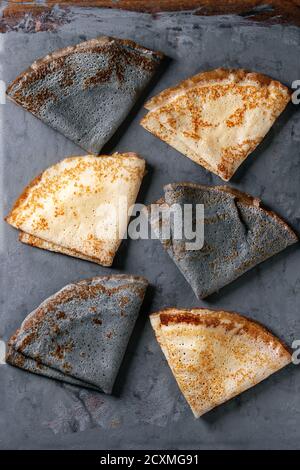 Varietà di nero e di bianco vuoto crepe e pancakes. Al di sopra di metallo grigio Sfondo. Vista superiore Foto Stock