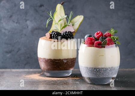 Vari dessert prima colazione a strati semi di Chia, budino di cioccolato, farinata di riso in vetro decorato da una fresca di more, Fette di pera, cacao in polvere. St Foto Stock