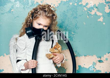 ritratto di una bambina di angelo in un respiratore maschera protettiva con un giocattolo in mano. concetto di ecologia pandemia epidemia Foto Stock