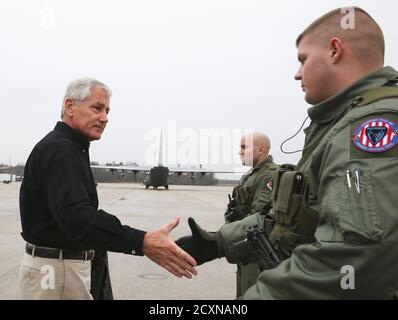 U.S. Secretary of Defense Chuck Hagel (L) greets two members of the US Air Force before boarding his aircraft to departing on an overseas trip at Joint Base Andrews, Maryland on December 5, 2014. REUTERS/Mark Wilson/Pool (UNITED STATES - Tags: MILITARY)