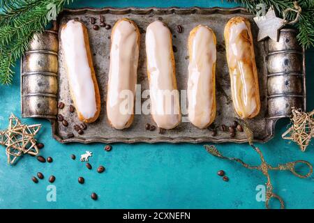 Caffè fatto in casa eclairs con caffè fagioli su vassoio di metallo vintage decorato da abeti e stelle su sfondo di legno turchese con spazio copia. Vi Foto Stock