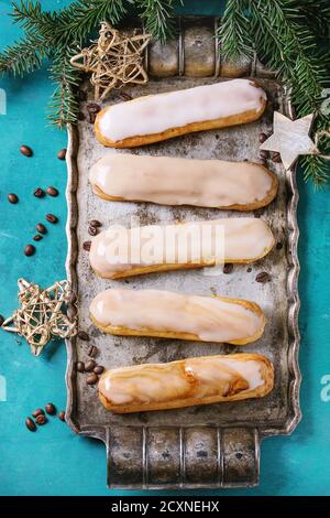 Caffè fatto in casa eclairs con caffè fagioli su vassoio di metallo vintage decorato da abeti e stelle su sfondo di legno turchese con spazio copia. Vi Foto Stock