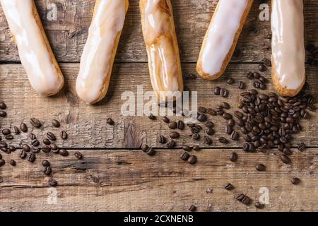 Freschi Fatti in casa eclairs caffè con diversi smalti e i chicchi di caffè più vecchio di legno sfondo texture con spazio per il testo. Vista dall'alto. Foto Stock