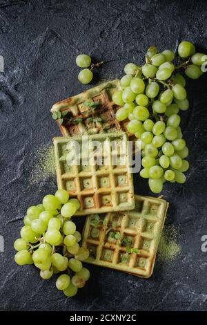 Cialde belghe matcha quadrate fatte in casa con grappa fresca matura e menta su fondo di pietra nera. Vista dall'alto con spazio Foto Stock