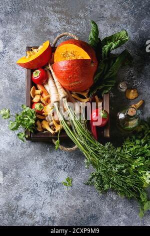 Variety of autumn harvest vegetables carrot, parsnip, chard, paprika, hokkaido pumpkin, porcini and chanterelles mushrooms in wooden tray over gray te Stock Photo