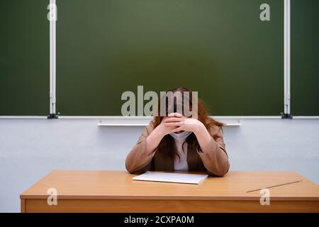 Triste insegnante siede sullo sfondo della lavagna, copia spazio Foto Stock