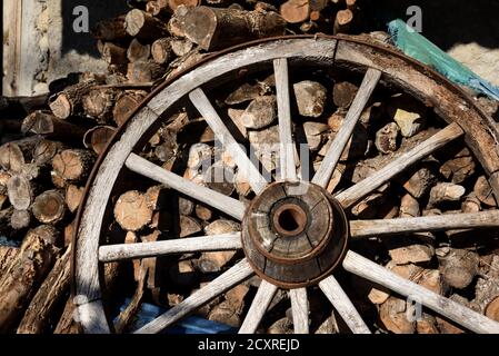 Vecchia ruota in legno con mozzo in legno rinforzato e raggi in legno & legna da ardere tagliata Foto Stock