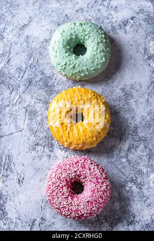 Variety of colorful glazed donuts over gray texture background. Top view with space Stock Photo