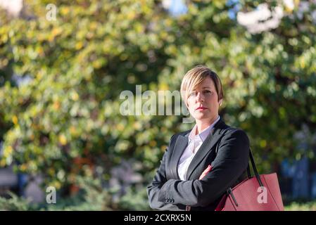 Donna d'affari allegra fuori in posa con le braccia incrociate Foto Stock