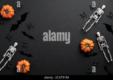 Halloween piatto composizione di posa. Scheletri, zucche, ragni, silhouette di pipistrelli su sfondo nero. Halloween banner mockup, biglietto d'auguri modello Foto Stock