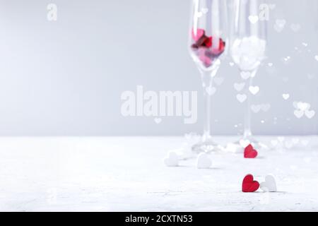 L'amore il giorno di San Valentino biglietto di auguri con due vuoti bicchieri di champagne e cuori di legno bianco su sfondo grigio. Copia dello spazio. Messa a fuoco selettiva Foto Stock