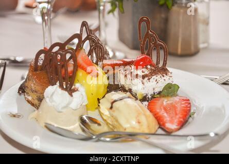 Sul piatto si ergono molti dolci diversi con panna e frutta. Colazione nel ristorante dell'hotel Foto Stock