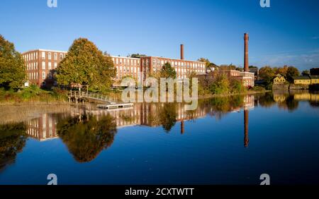 Un xix secolo mulino tessile è stato rinnovato per un uso moderno, visto riflesso nel fiume vicino a Exeter, New Hampshire Foto Stock