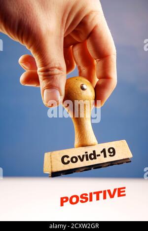 Timbro in gomma Covid 19 in mano con testo positivo bianco Foto Stock