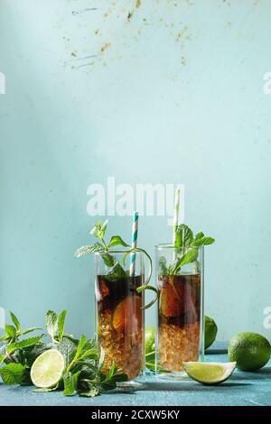 Due bicchieri di classic cuba libre cocktail con calce, menta, ghiaccio tritato e cola, servita con gli ingredienti di cui sopra e cocktail retrò tubi su turquois Foto Stock