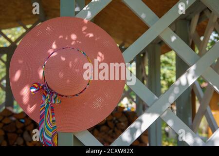 Un cappello rosa con un arco pende sul gazebo estivo. Foto Stock