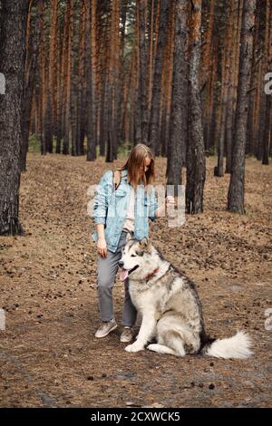 Giovane ragazza con il suo cane, Alaskan Malamute, all'aperto in autunno. Animali domestici Foto Stock