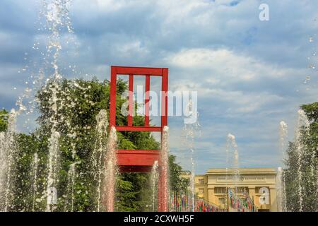 Ginevra, Svizzera - 16 agosto 2020: Sedia rotta con fontane, scultura monumentale in legno in Place des Nations di fronte al Palazzo delle Nazioni Unite, A. Foto Stock