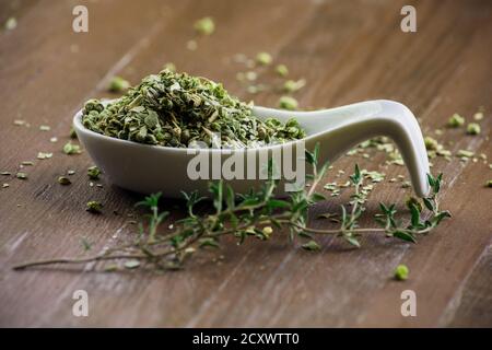 Timo verde secco e fresco in cucchiaio di porcellana su fondo marrone. Foto Stock