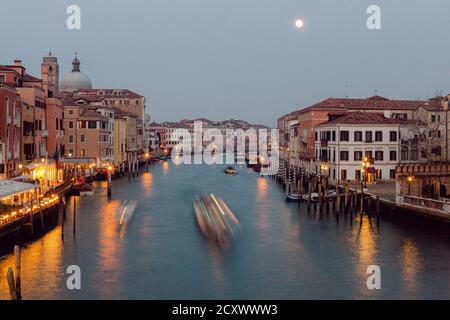 Vita notturna a Venezia: Vista a lunga esposizione sul Canal Grande, con barche, luci artificiali e traffico cittadino lento Foto Stock