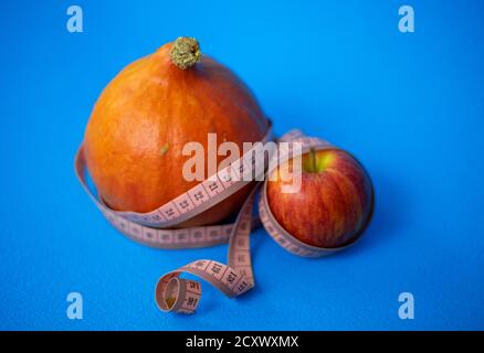 Dieta sana. Zucca e mela con nastro centimetrico su sfondo blu Foto Stock
