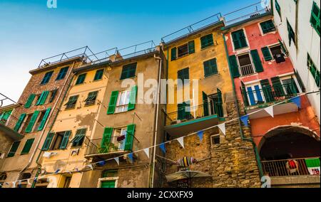Grande vista ravvicinata delle storiche case a torre colorate con tipiche persiane verdi sulla strada Via San Giacomo a Riomaggiore, la... Foto Stock