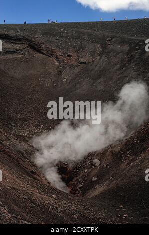 I turisti che esplorano le zone al di sotto della pericolosa cima dell'Etna, la Sicilia, l'Italia, sono avvertiti di evitare i bordi di crateri, fessure e sfiati che fiaccano le nuvole di vapore e gas dal profondo all'interno della montagna. I visitatori possono accedere alle zone autorizzate del cratere "‘safe" a 9,590 m in funivia o minibus 4x4 e partecipare a visite guidate ufficiali a piedi, anziché rischiare di spostare da soli cenere, legnoli e pietre sciolte. L'Etna, il vulcano attivo più alto d'Europa, è in eruzione da circa 500,000 anni, con molte recenti eruzioni da sfiati sui fianchi e dalla cima. Foto Stock