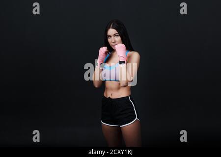 Sportivo muay thai donna boxer ritratto posizione in studio su sfondo nero. Foto Stock