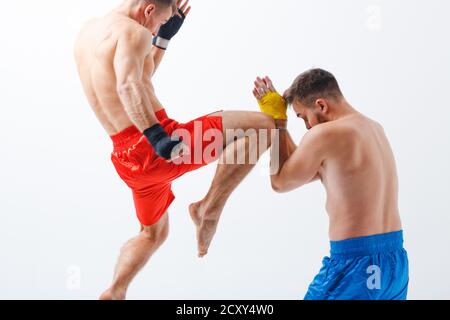 Due uomini boxer lotta muay thai kick ginocchio in salto pugilato sfondo bianco. Sfocatura del movimento. Foto Stock