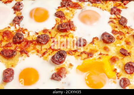 frittura con polenta con salsiccia e uova in camicia (uova soleggiate) nei nidi, cotte in forno Foto Stock