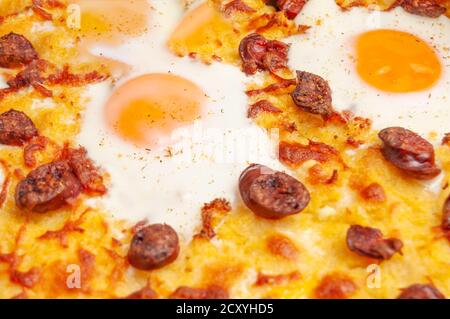 frittura con polenta con salsiccia e uova in camicia (uova soleggiate) nei nidi, cotte in forno Foto Stock