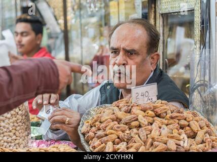 New Delhi, India - 19 Febbraio 2018 - Uomo Vendita di noci e frutta secca parla al cliente che si è rivolto Foto Stock