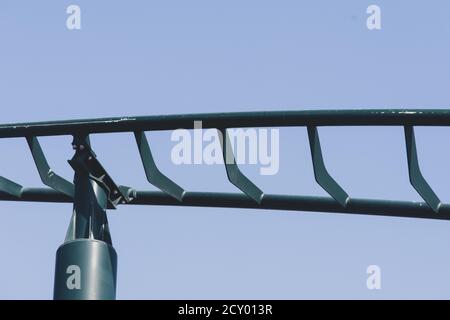 Primo piano di Rollercoaster in un parco a tema o di divertimento vuoto verde piste di metallo e su sfondo blu cielo. Foto Stock